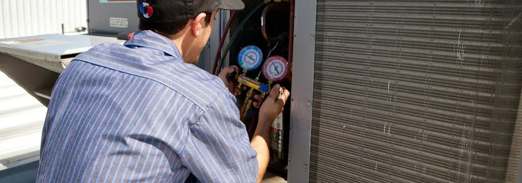 HVAC technician servicing a condenser unit in Mason City