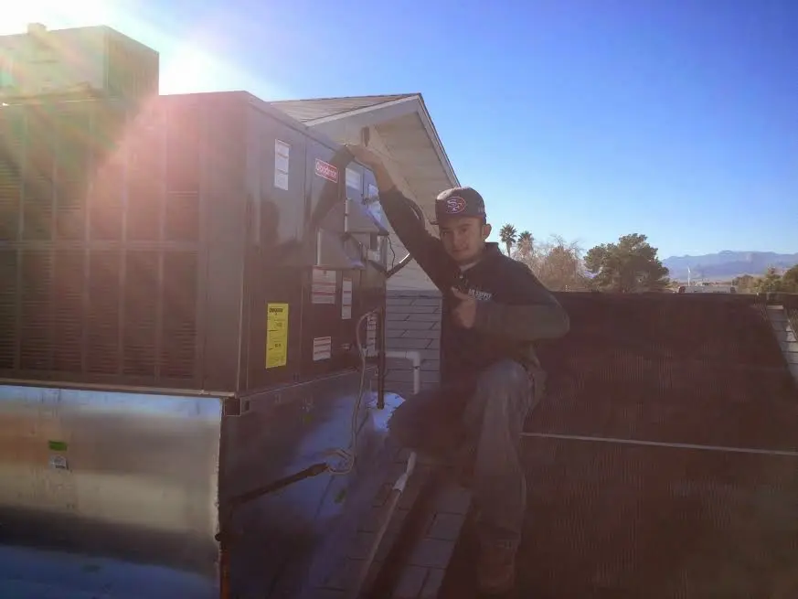 HVAC technician performing AC Tune-Up on a rooftop unit in Mason City